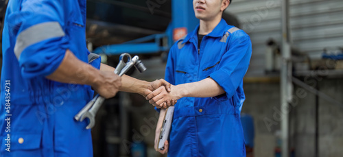 Two car mechanic team shaking hand at automobile service center. Repair service concept. Car repair and maintenance. Car mechanic working at automotive team service center