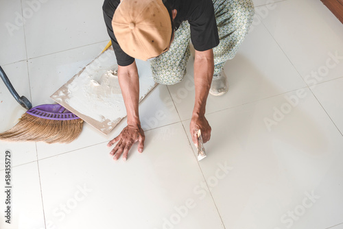 A handy man prepares the edge of floor tiles for the application of new grout to fill the gaps. Home renovation or finishing works. photo