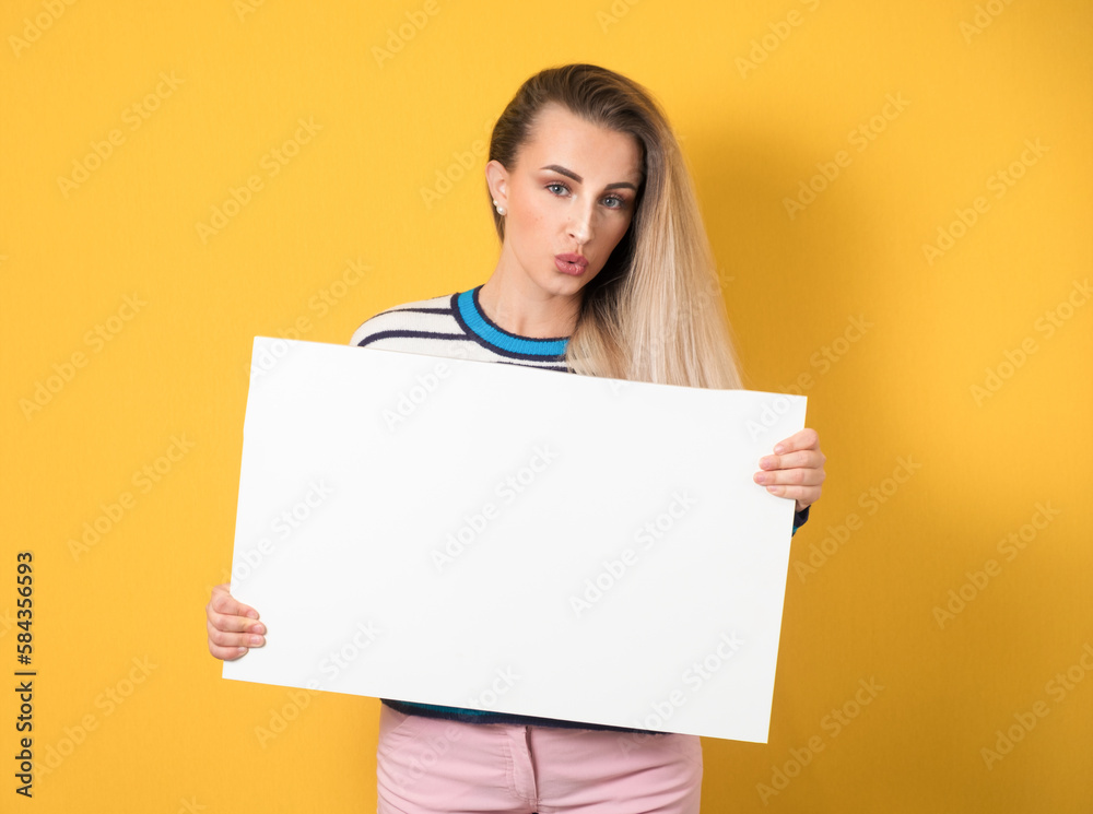 Surprised promoting women holding white board, isolated on yellow background. Girl showing blank empty paper billboard with blank space for text Surprised promoting women holding white board, isolated on yellow background. Girl showing blank empty paper billboard with blank space for text