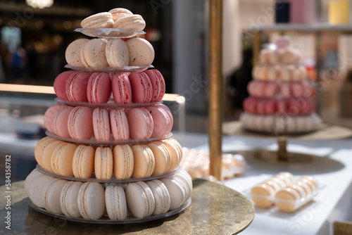 Delicious macarons in soft pastel shades are piled on a plate in a market stall. Blurred background