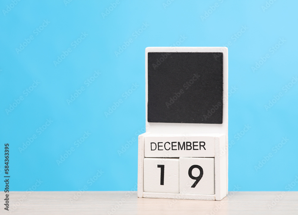 White wooden block monthly calendar with the date december 19 on the table, blue background. Planning, deadline White wooden block monthly calendar with the date december 19 on the table, blue background. Planning, deadline