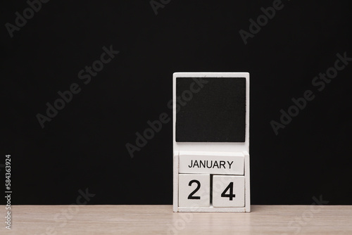 White wooden block monthly calendar with the date january 24 on the table, black blackbackground. Planning