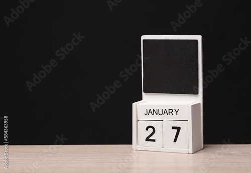 White wooden block monthly calendar with the date january 27 on the table, black blackbackground. Planning