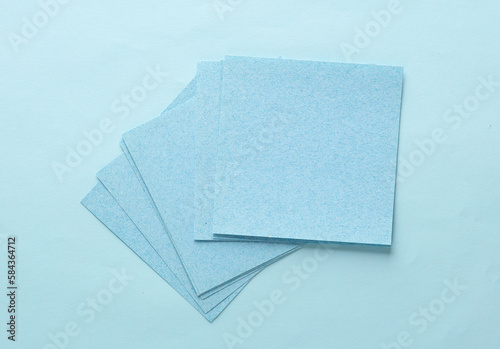 Stack of blue square memo sheet of papers on blue background. Top view © splitov27