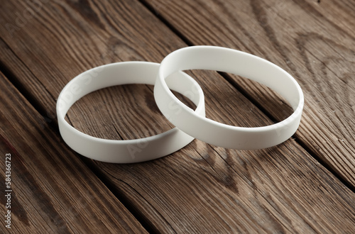 White silicone bracelets on a wooden table. Template for design