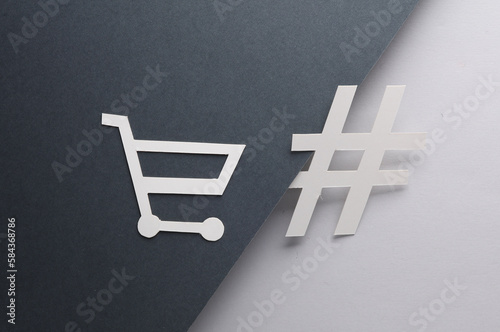 Paper cut shopping trolley with hashtag on black gray background. Sale, creative layout