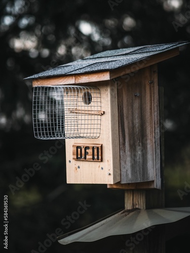 Vertical closeup of a cute little wooden birdhouse on a blurred background with bokeh in the wild