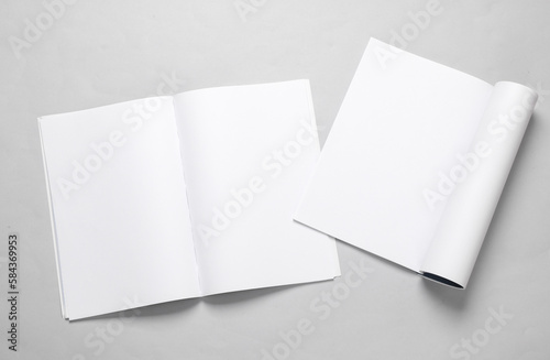 Mockup of two open magazines with white open pages on a gray background. Template for design