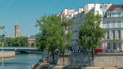 Saint-Louis bridge timelapse with houses on Orleans waterfront. Two islands on the River Seine in Paris, France, called Ile de la cite and Ile saint Louis. Tower on oa background. Paris, France. photo