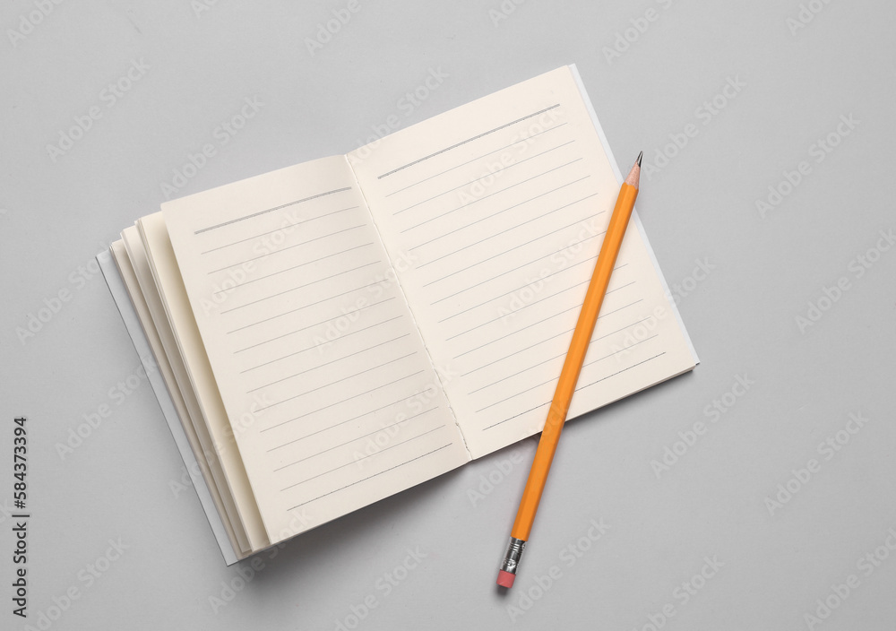 Open notepad with pencil on gray background Open notepad with pencil on gray background