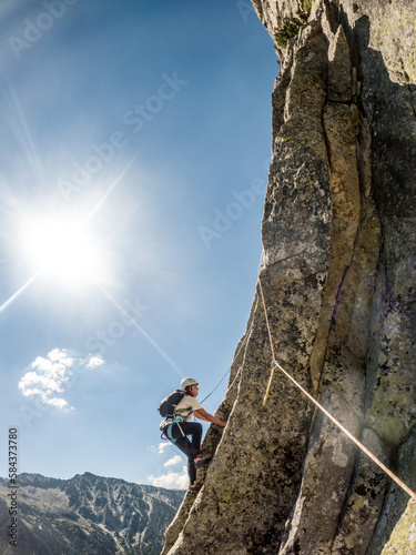 woman climbing in the middle of the mountain, ropes, lake, forest