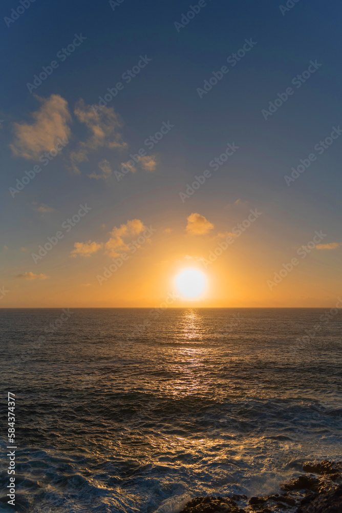 panorámica Impresionante puesta de sol desde los acantilados de la costa de Fuerteventura en un día de verano con cielo despejado y un gran sol bajo sobre el mar. Recursos naturales de Canarias