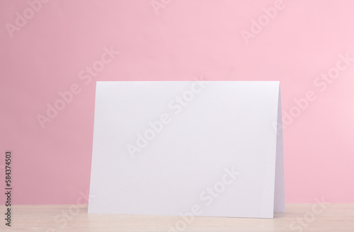 Pack of white paper desk calendar or announcement on the table, pink background