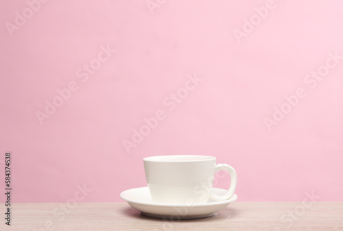 Ceramic white coffee cup on the table, pink background