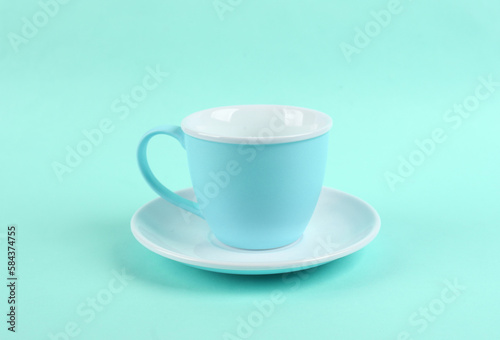 Empty ceramic cup and saucer on blue background