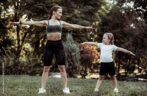 Active family concept. Fit mom with little daughter practice outdoor exercises in the park. Healthy lifestyle. Physical Education © splitov27