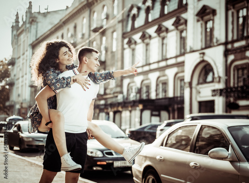 Couple in love. Man carrying girl on his back in the street. Smiling man with beautiful young woman, ride piggyback, having fun together. Relationship concept. © splitov27