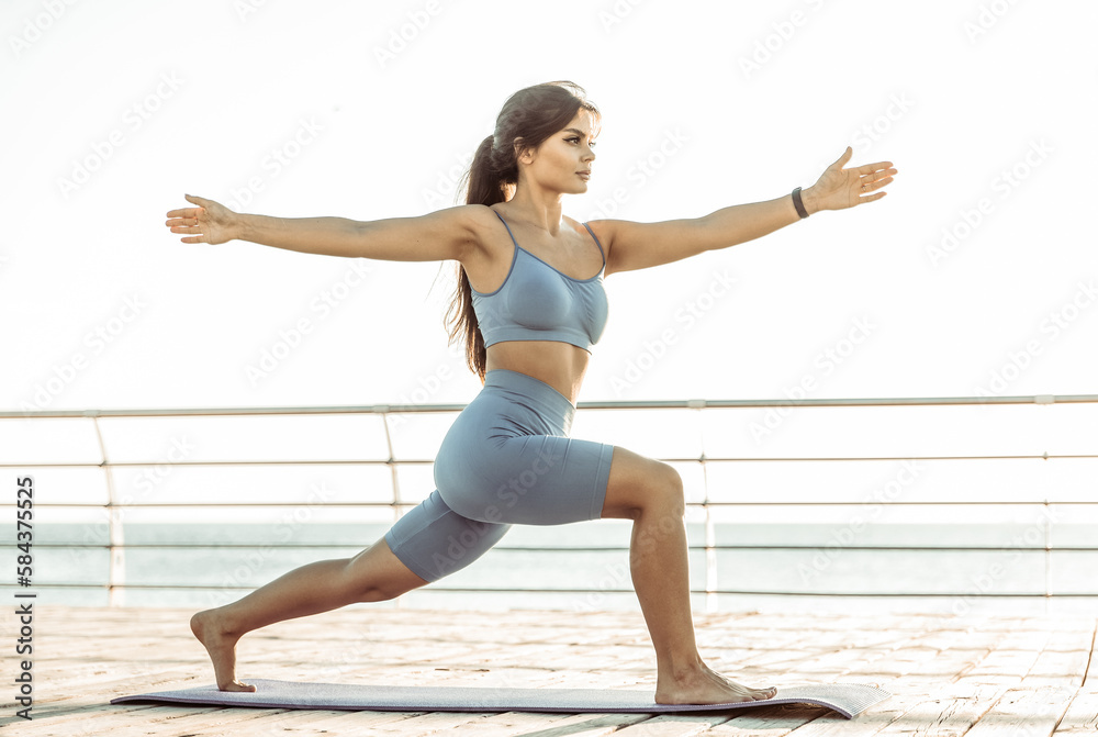 Young beautiful fit woman practicing yoga on the beach