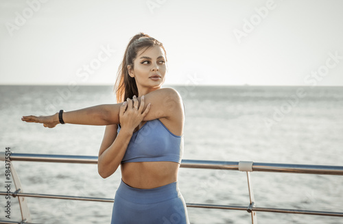 Fit woman practicing hand stretching on the beach. Active lifestyle © splitov27