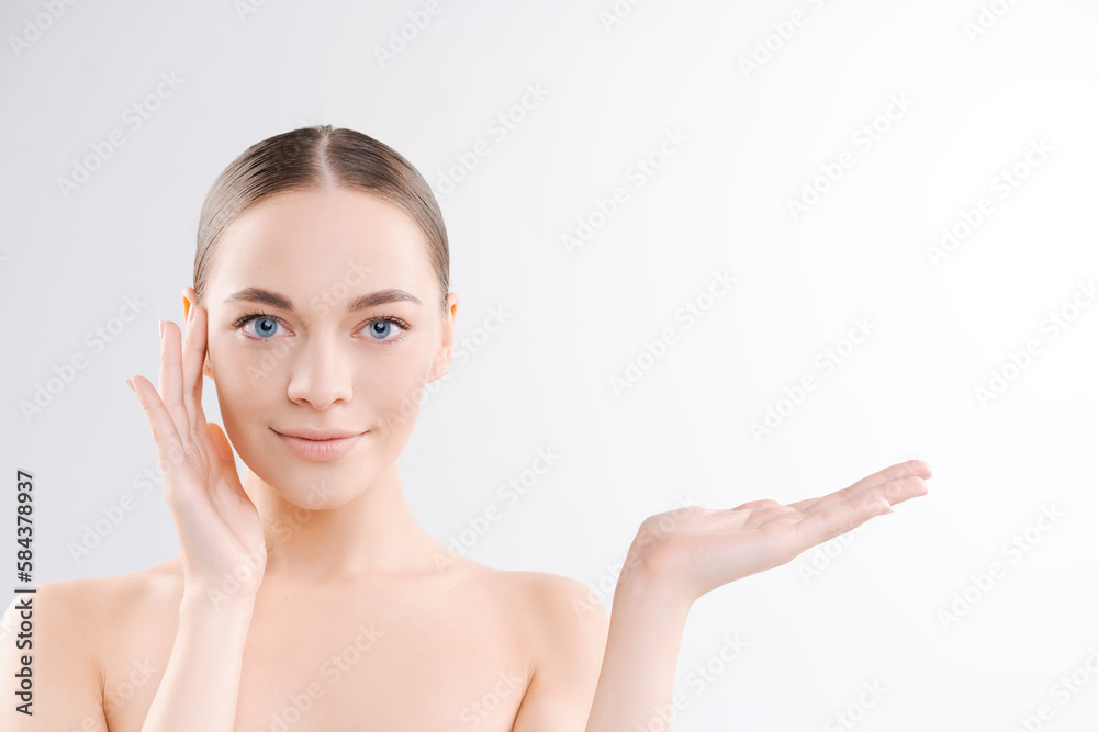 Beauty spa with perfect skin portrait. Beautiful Brunette Spa Girl showing blank copy space on open hand for text. Product offer. Gestures for advertising. Light background in the studio Beauty spa with perfect skin portrait. Beautiful Brunette Spa Girl showing blank copy space on open hand for text. Product offer. Gestures for advertising. Light background in the studio