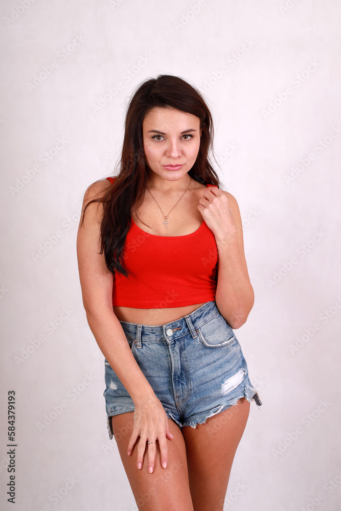 beautiful brunette in blue denim shorts and a red t-shirt beautiful brunette in blue denim shorts and a red t-shirt
