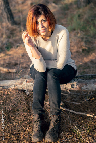 Girl sitting in the forest at sunset smoking © Juan Garcia