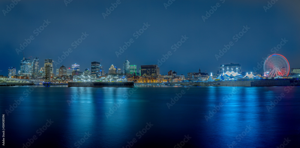 a panoramic night view of the Grand Quai de Monteal with its Ferris wheel and the big top, with the illuminated city in the background