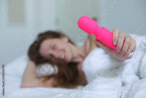 Konstfotografi Young happy sexy woman hold in hand sex toy, masturbate with vibrator in bed in bedroom at home