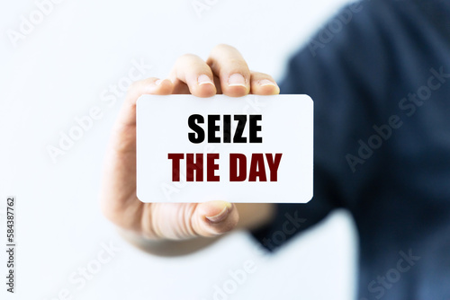 Obraz na plátně Seize the day text on blank business card being held by a woman's hand with blurred background