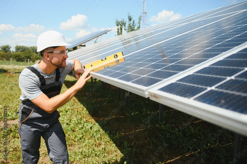 Male engineer in protective helmet installing solar photovoltaic panel system. Alternative energy ecological concept. Male engineer in protective helmet installing solar photovoltaic panel system. Alternative energy ecological concept.