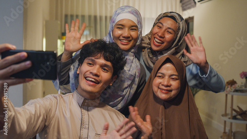 Cuadro en lienzo Happy Asian muslim family greeting celebrate long distance with cousin use cell phone video call online Ramadan dinner together at home