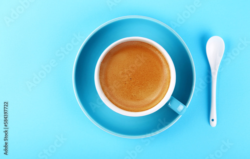 Full cup of espresso coffee on blue paper