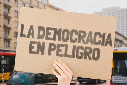 The phrase " Democracy in danger " is on a banner in men's hands with blurred background. Politics. Problem. Solution. Protest. Political crisis. Collapse. Crush