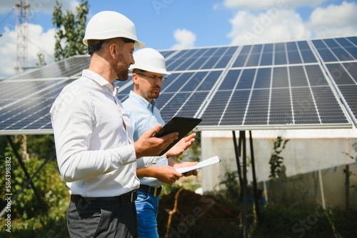 The solar farm(solar panel) with two engineers walk to check the operation of the system, Alternative energy to conserve the world's energy, Photovoltaic module idea for clean energy production © Serhii