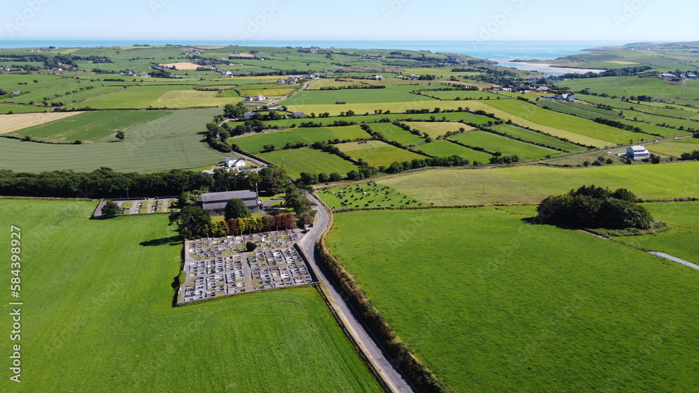 A cemetery near the Sacred Heart Roman Catholic Church, top view. Picturesque green farm fields on a sunny summer day.