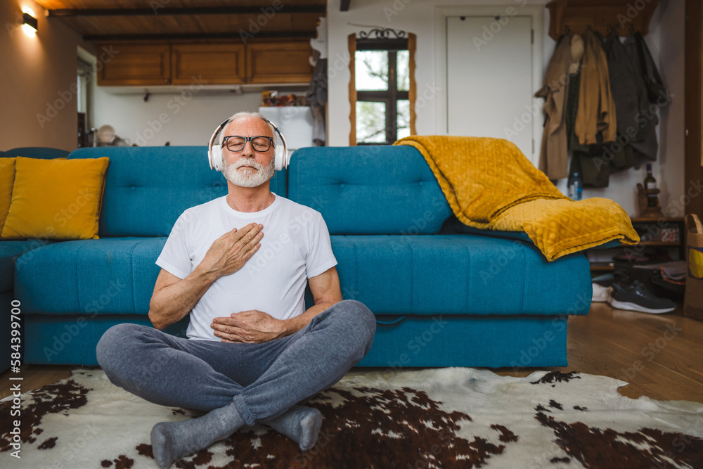 Obraz premium One senior man doing guided meditation yoga self care practice at home