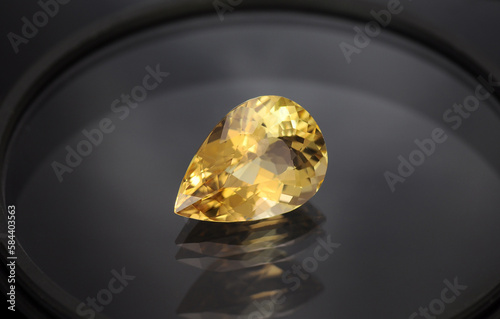 Golden yellow color natural heliodor beryl drop shaped loose faceted gemstone setting. Clean, transparent unheated genuine stone for making jewelry. Multiple reflection on glass surface. Gemology. photo