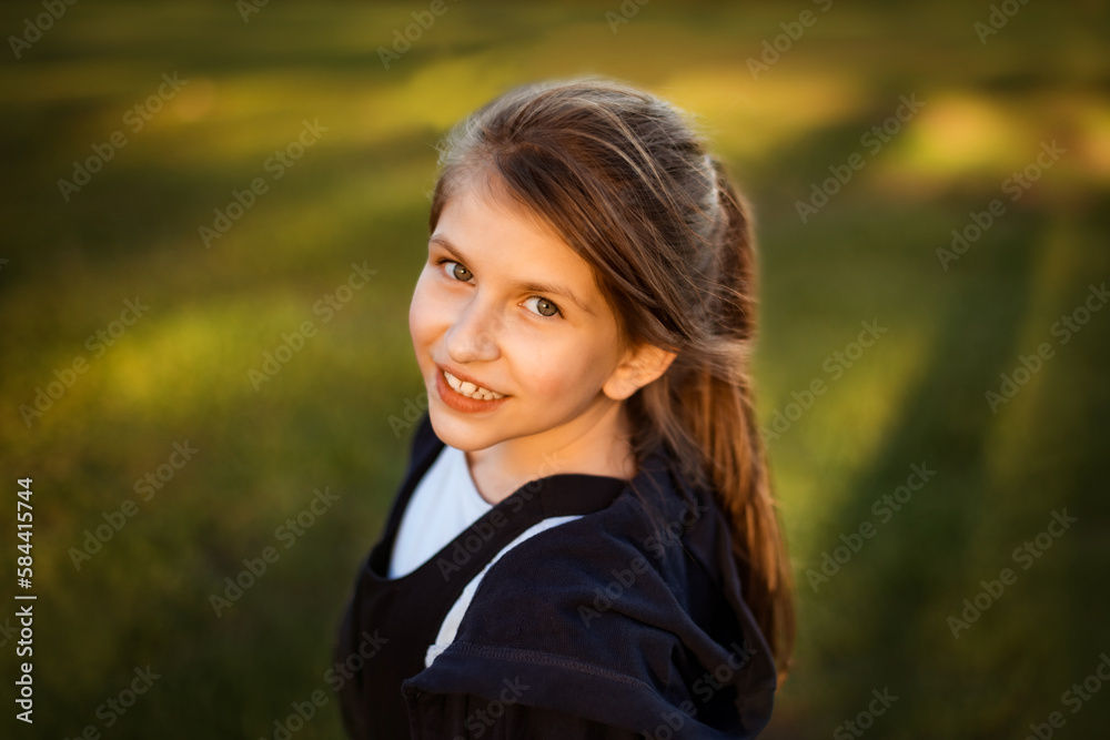 portrait of teenage girl on green grass background school yard with long shadows looking at camera portrait of teenage girl on green grass background school yard with long shadows looking at camera