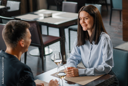 A date in a hotel restaurant a man and a woman drink white wine in glasses the face of a smiling girl