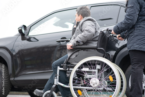 A woman helps aphysical disabled person to get into the car