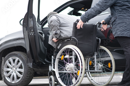 A woman helps aphysical disabled person to get into the car