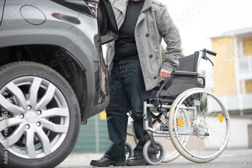 Person with a physical disability puts purchases in the trunk of a car in a supermarket parking lot