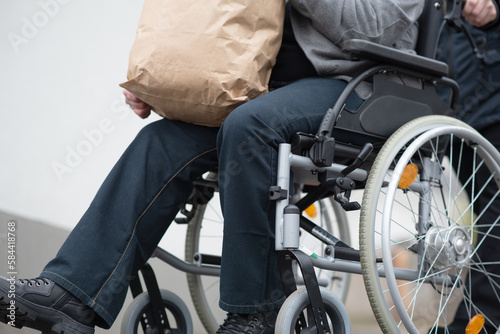 a woman pushes a physically disabled person in a wheelchair after shopping