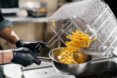 professional kitchen in the restaurant of the hotel the chef takes out delicious french fries from the fryer
