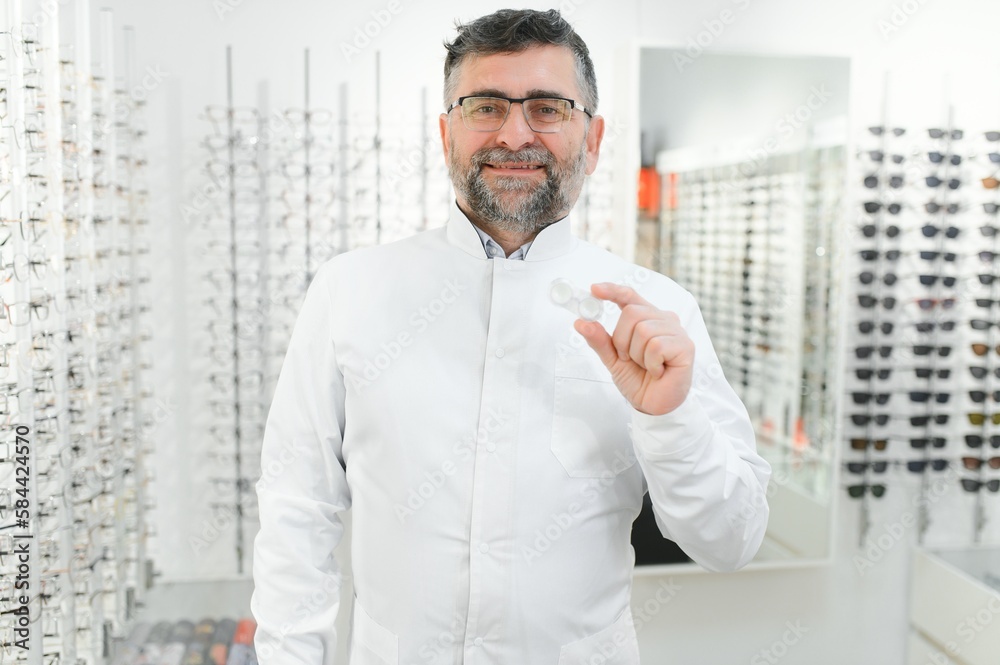 Fototapeta premium Doctor holds in his hand container with soft contact lenses for single use. Ophthalmologist prescribes use of one-day contact lenses for vision correction. Myopia and eyesight problem concept.