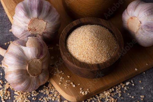 Dry garlic granules. Spice garlic. Dry garlic powder in a wooden bowl and spoon.