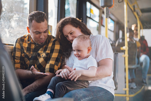 Happy parents and son riding in bus while baby sits in mother lap.
