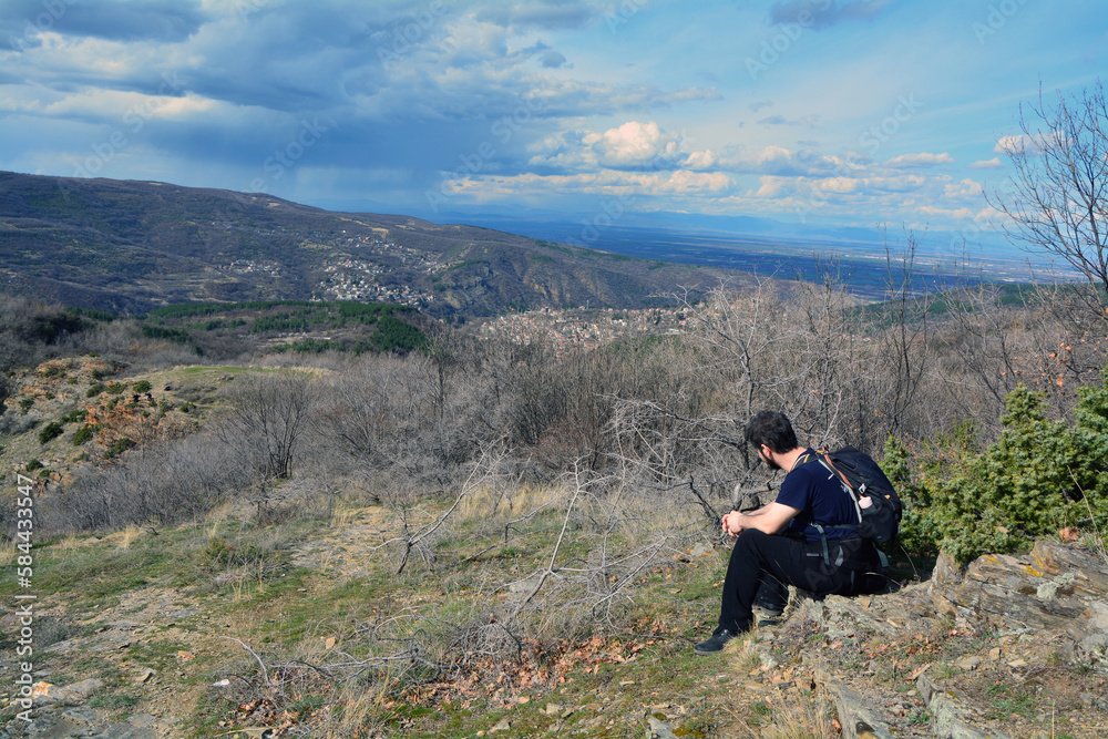 A man with a backpack resting and contemplating scenic panorama