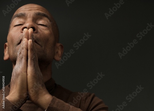 man praying to god with hands together Caribbean man praying with black background stock photos stock photo 