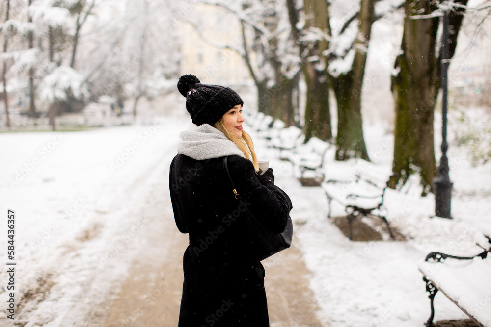 Young woman in warm clothes enjoying in snow with takeaway coffee cup Young woman in warm clothes enjoying in snow with takeaway coffee cup